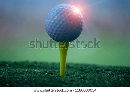 Golf ball on tee in beautiful golf course at sunset background. 