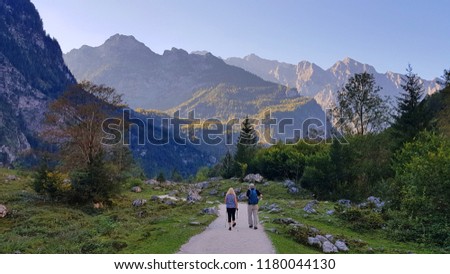 A couple walks on a hiking path in a beautiful valley surrounded by alps mountains