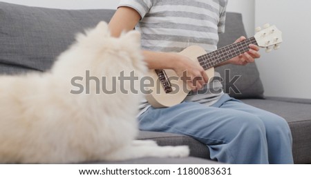 Pet owner play ukulele with her dog
