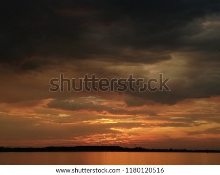 Vivid colored mystic sky, dark silhouette, ray of lights and warm water