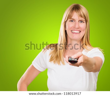 Portrait Of A Happy Woman Holding Remote Control against a green background