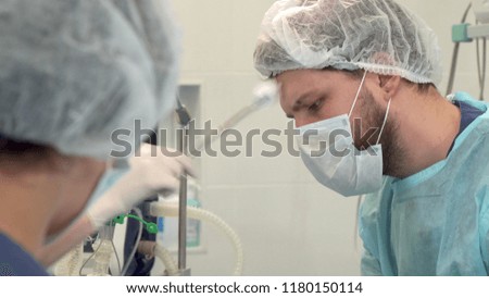 Surgical team using sterilized instruments at the surgery. Close up of young caucasian surgeon operating patient. Surgical nurse wiping doctors face by piece of wadding