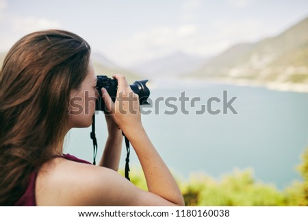 Young tourist Girl taking pictures of mountains and lake. Georgia. Summer. August. Girl making a photo shoot of mountain.