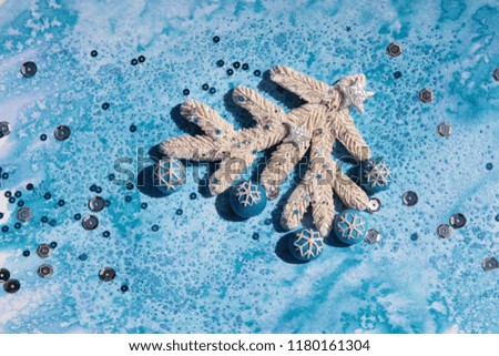 Plasticine white branch of Christmas tree decorated in blue and silver colors, with sequins, stars and snowflakes on an abstract blue watercolor background with sea salt