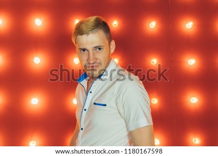 Masculine brunette man 30s with stubble in white shirt looking on camera over red background