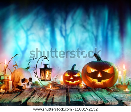 Jack O' Lanterns And Candles On Table In Misty Forest - Halloween Background