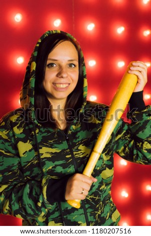 Young pretty girl with baseball bat, girl with bat. a girl or criminal holding a baseball bat in her hand on a red background. Sports and training
