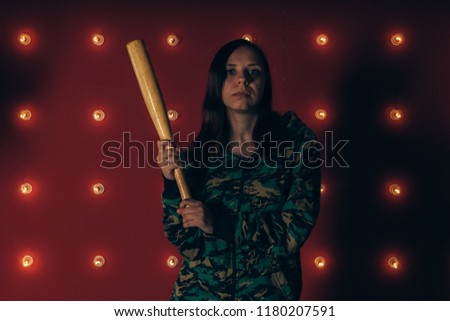Young pretty girl with baseball bat, girl with bat. a girl or criminal holding a baseball bat in her hand on a red background. Sports and training
