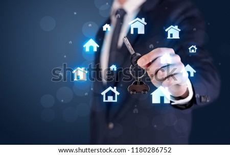 Businessman in suit holding keys with house graphics around and dark background