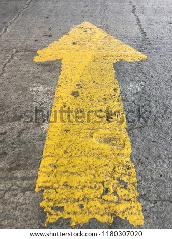 A yellow arrow painted on the pavement