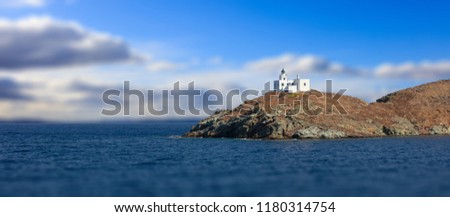 Lighthouse and agios Nikolaos church on rocky land. Kea,Tzia the sunny island, Greece. Blur cloudy sky background, banner.