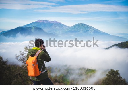Photographer or Traveller using a professional DSLR camera take photo landscape of Kawah Ijen volcano mountain, the most famous tourist attraction in Indonesia - Recreation and outdoor travel concept.