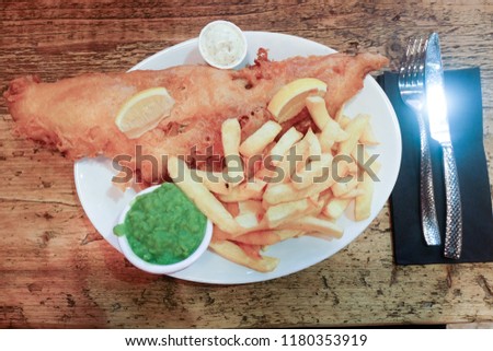 A flatlay picture of large cod fish serve with chips and green peas in Conwy.