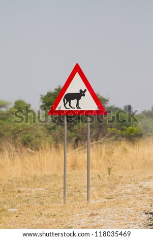 A sign post with a picture of an African wild dog on it