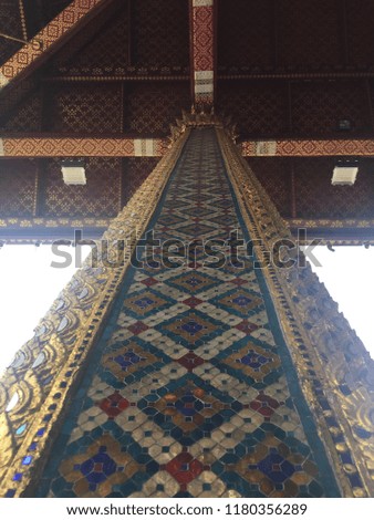 beautiful scene of looking up at classic ancient art temple pole that ornament with colorful mosaic in thailand (public place)