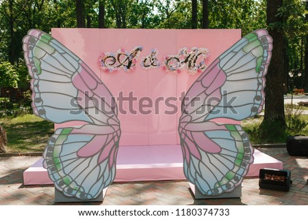Pink shiny photo wall for wedding banquet. Mr. & Mrs. signs decorated by big butterfly wings.