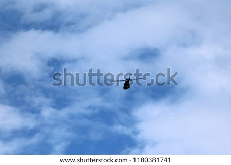 A flying black helicopter aircraft during the flight with blue sky 