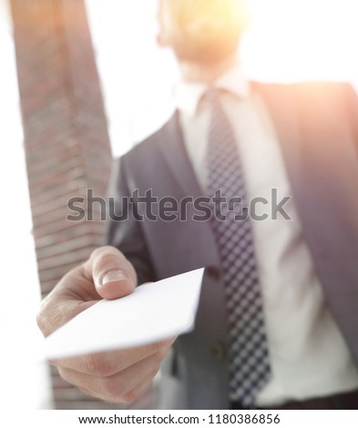 Businessman giving a card. Close-up photo in loft office