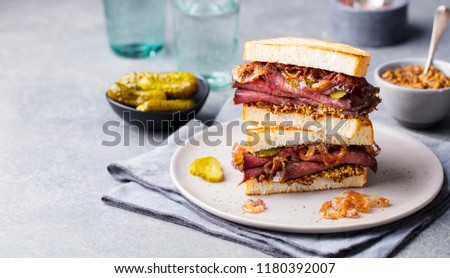 Roast beef sandwich on a plate with pickles. Copy space.