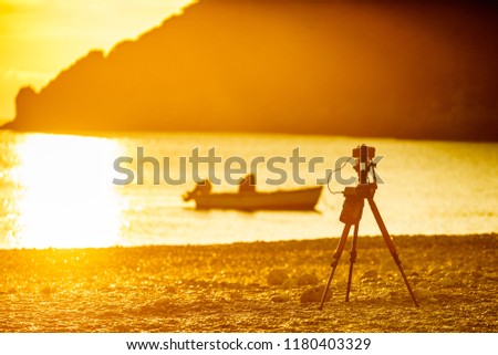 Professional camera taking picture film video of scenic orange sunrise or sunset over sea surface, Greece Peloponnese.