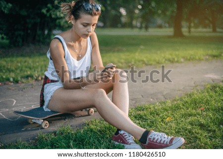 Young girl uses smartphone in the park. Summer. Holidays. Sport. Free time. 