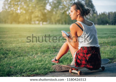Young girl uses smartphone in the park. Summer. Holidays. Sport. Free time. 