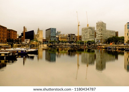 A picture of some tall building with reflection infront of Liverpool famous dock before raining.