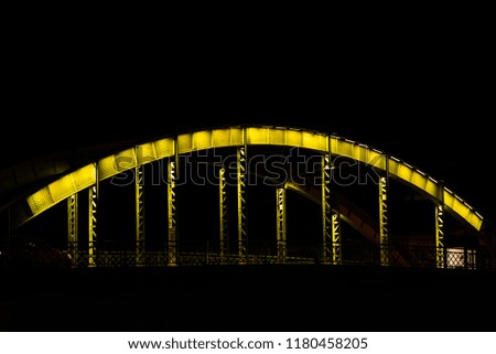 An old steel bridge in various colors, during the night