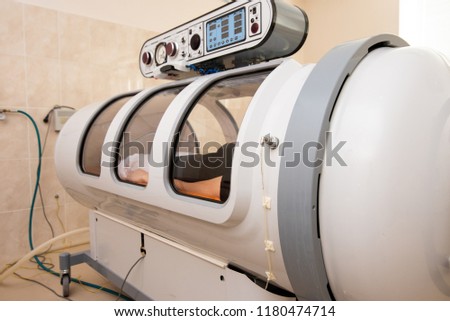 beautiful girl in a black T-shirt and white pants lies in a hyperbaric chamber Royalty-Free Stock Photo #1180474714