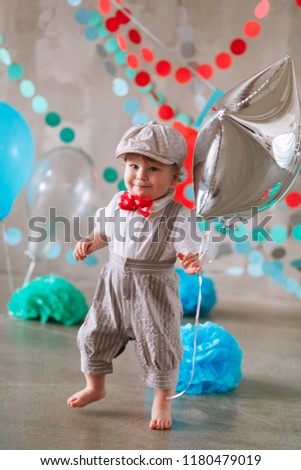 year-old boy in suit standing in decorated studio room looking up. Full-lenght vertical portrait.