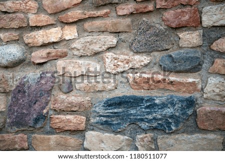 Stone texture, fragment of ancient crumbling fortress wall of granite bricks and stones