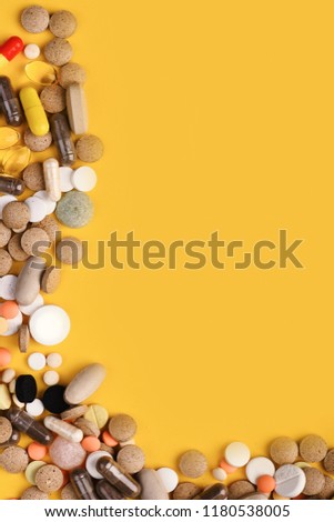 Medicine and treatment concept. Frame made of round pills and capsules put on one side. Drugs placed in corner. Set of colorful pills scattered on yellow background, copy space