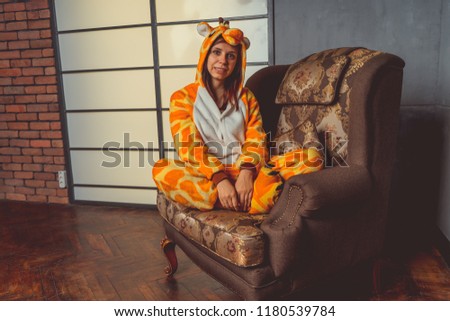 Pajamas in the form of a kangaroo. emotional portrait of a student on the background leather sofa. Crazy and funny girl in a suit. Animator for children's parties