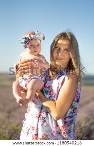 Young mother and baby with a bow on her head in a flowering lavender field