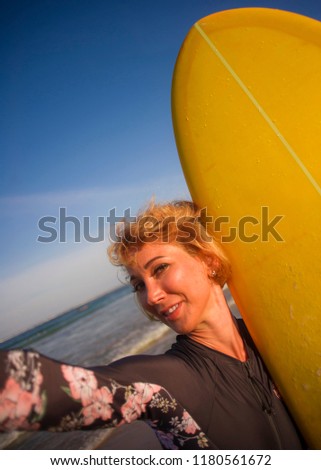 young attractive and happy blonde surfer woman in swimsuit holding surf board in the beach taking self portrait selfie picture smiling cheerful enjoying holidays at tropical island