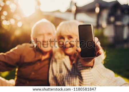Close up of handy screen in female arm. Cheerful smiling couple at blurred background