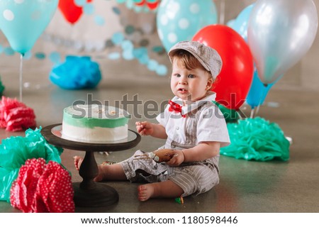 little baby boy eating cake on his first birthday cakesmash party.