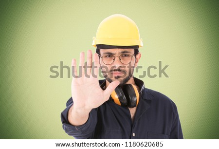 Close up shot of repairman raises his palm with a frowning face doing the stop sign, over blurred green background.