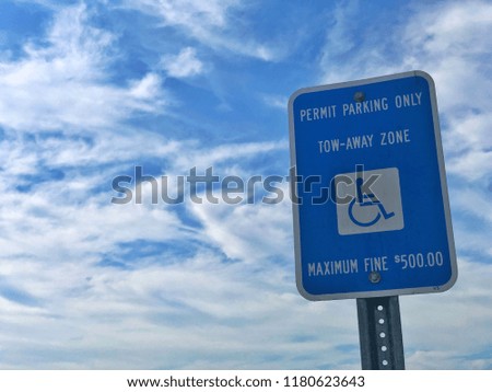 Permit parking sign for disabled persons set against cloudy blue sky