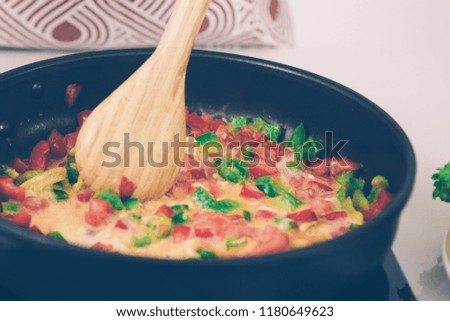 Closeup of wooden spoon and omelet with vegetables in pan. Picture for menu. Cooking and meal concept