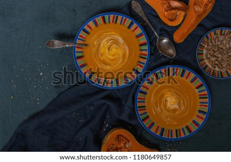 Bowl of pumpkin organic soup with cream and pumpkin seeds on gray background. Dietary vegetarian food. Concept of healthy eating food. Homemade autumn soup. Top view with copy space. Toned image.