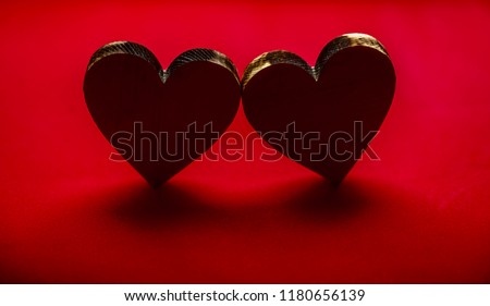 two wooden hearts standing on red background. 