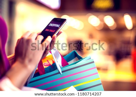 Female customer with mobilephone and shopping bags in the mall. Shopping online, big sale concept