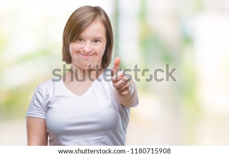 Young adult woman with down syndrome over isolated background doing happy thumbs up gesture with hand. Approving expression looking at the camera with showing success.