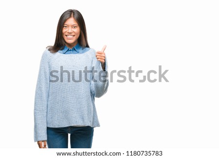 Young asian woman wearing winter sweater over isolated background doing happy thumbs up gesture with hand. Approving expression looking at the camera with showing success.