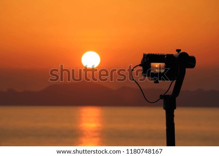Videos Camera on a Gimbal Stabilizer tripod on the beach. Red sky sunset background