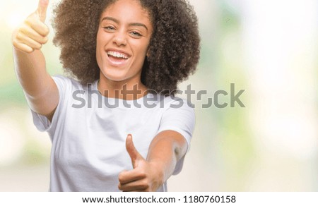 Young afro american woman over isolated background approving doing positive gesture with hand, thumbs up smiling and happy for success. Looking at the camera, winner gesture.