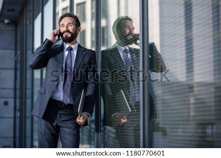 Business world. Cheerful delighted businessman talking on phone and smiling