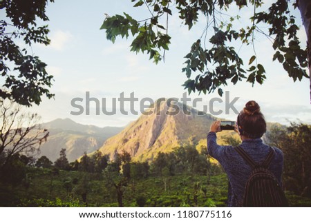 Girl tourist photographing mountains and tea plantations in Sri Lanka