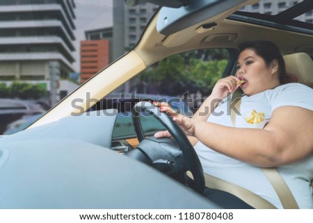 Picture of fat woman enjoying french fries while having a traffic jam on the road